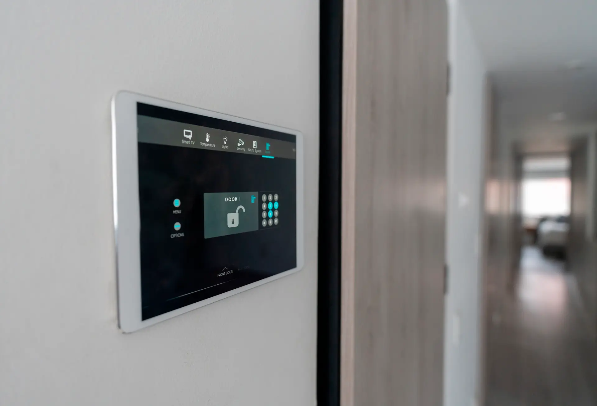 Un pannello di controllo moderno montato sulla parete, con un'interfaccia digitale che mostra diverse opzioni tra cui la sicurezza, luci e temperatura. Un'icona sulla schermata rappresenta una porta sbloccata
